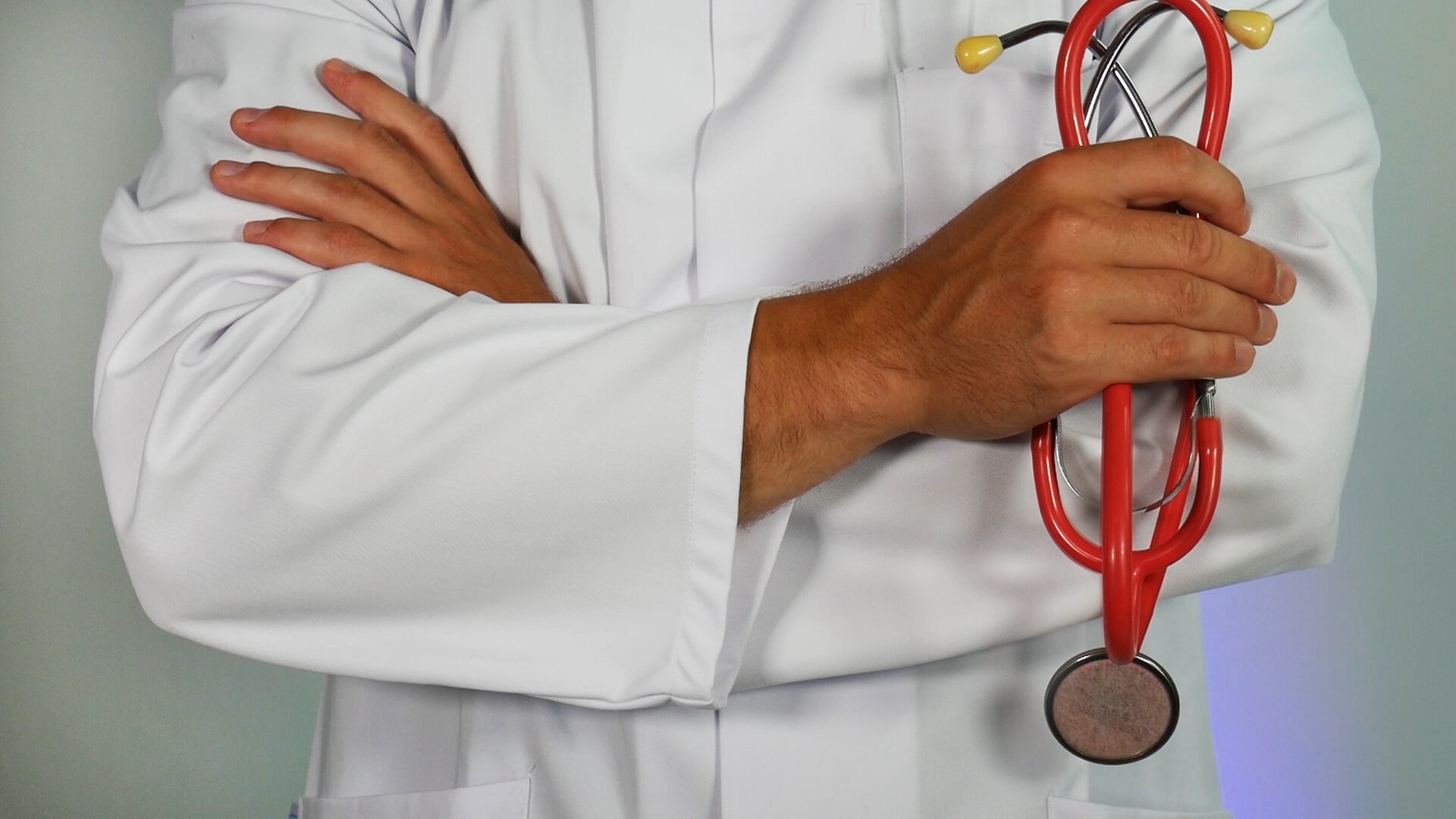 person standing with stethoscope in hand, arms crossed.